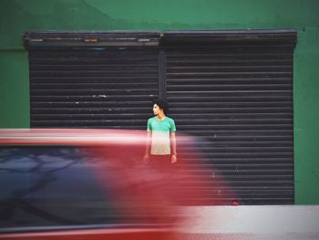 Blurred motion of car on road against man standing on sidewalk