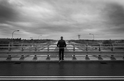 Rear view of man standing on bridge against sky