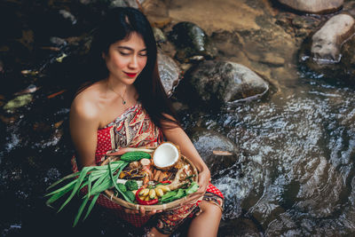 Portrait of young woman sitting on rock