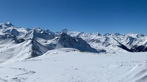 Scenic view of snow covered mountain against blue sky