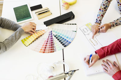 Cropped image of business people working on color swatches at desk in creative office