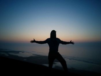 Silhouette of man standing on beach at sunset