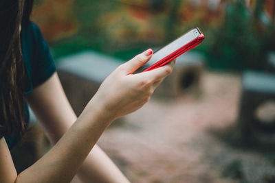 Midsection of woman holding mobile phone outdoors