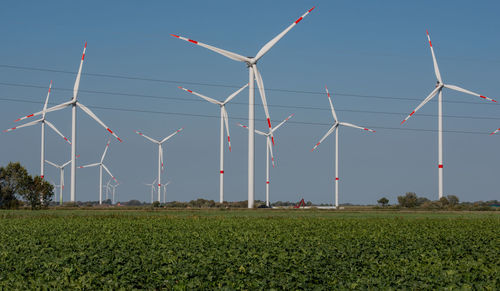 Wind turbines on field against clear sky