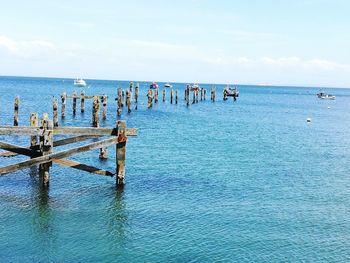 Group of people on pier at beach against sky