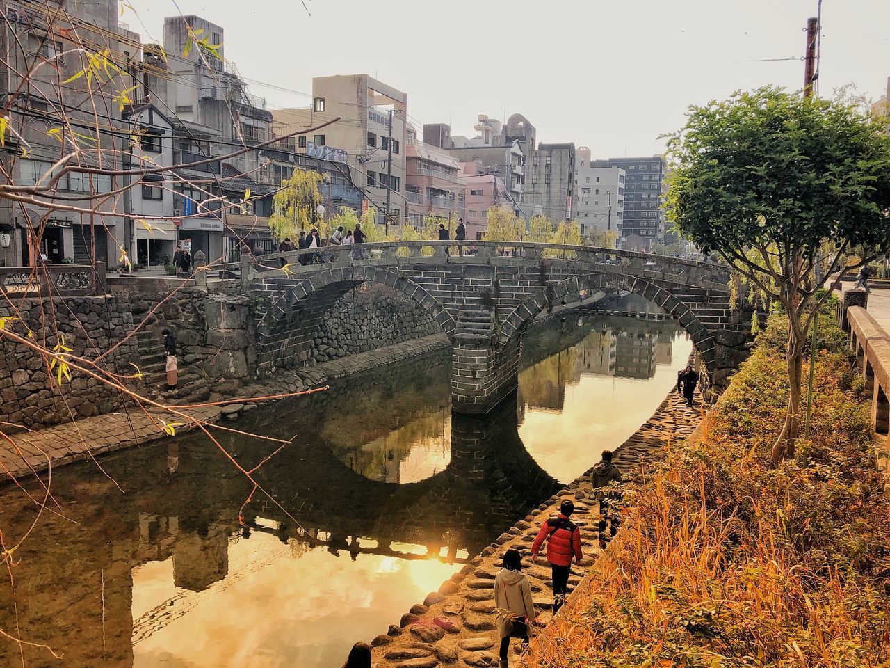 HIGH ANGLE VIEW OF BUILDINGS AND TREES BY CANAL