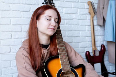 Portrait of young woman playing guitar