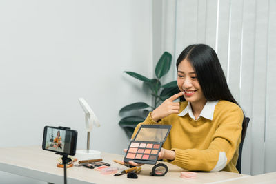 Woman using phone while sitting on table