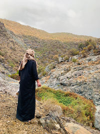 Rear view of woman standing on mountain against sky