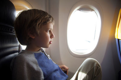 Boy looking through airplane window