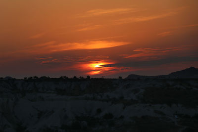 Scenic view of dramatic sky over silhouette landscape during sunset