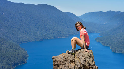 Hiker girl is on top of the mountain overlooking deep blue lake