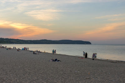 People on beach against sky during sunset