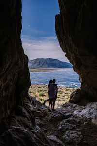 Rear view of man standing on rock by sea