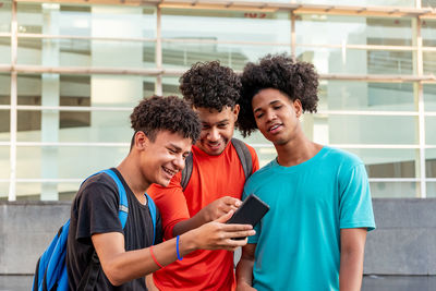 Friends using mobile phone while standing outdoors