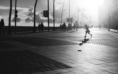 People on sidewalk in city against sky