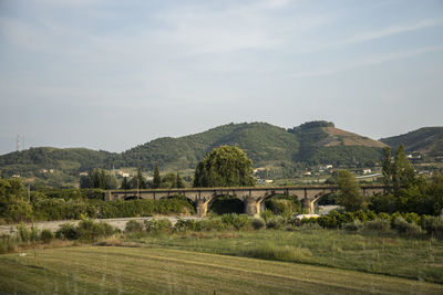 Arch bridge on field against sky