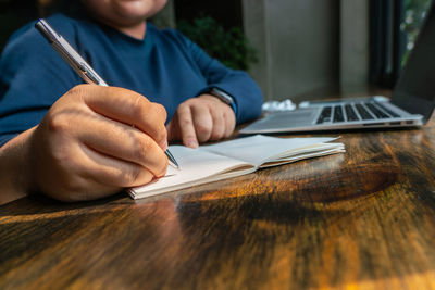 Midsection of man holding paper on table