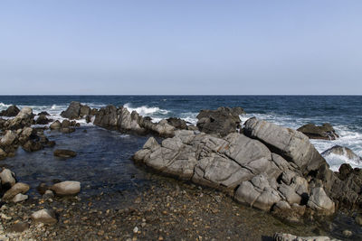 Rocks on beach against clear sky