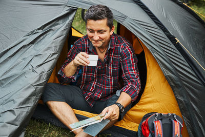 Man relaxing in tent at camping during summer vacation. man planning next trip. camp life