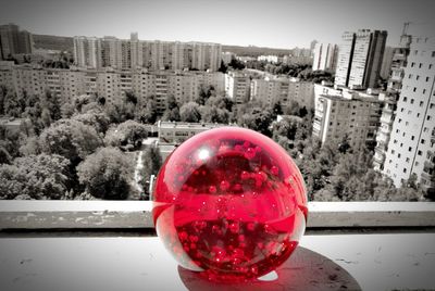Close-up of red wine glass against cityscape