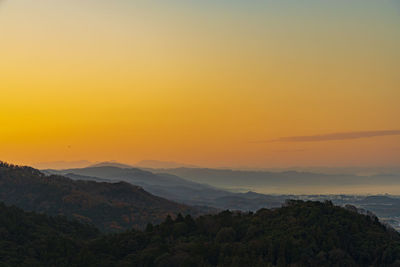 Scenic view of silhouette mountains against orange sky