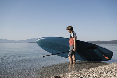 Rear view of man on boat in sea against clear sky