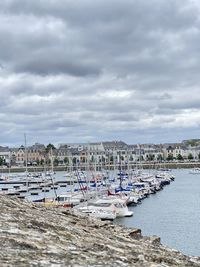 Boats moored at harbor against sky