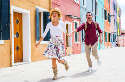 Young couple smiling on footpath in city