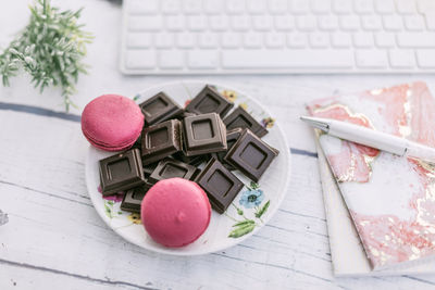 High angle view of chocolates with macaroons in plate on table