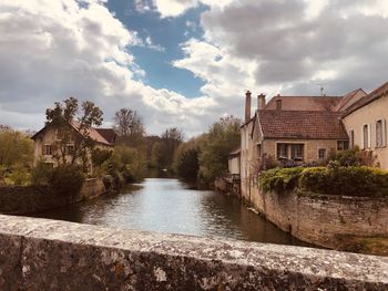 River amidst houses and buildings against sky