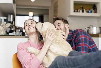 Happy young couple cuddling with dog at home