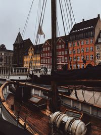 Sailboats moored at harbor against buildings in city