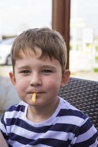 Close-up portrait of cute boy eating french fries