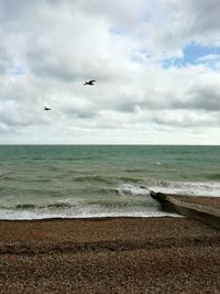 Scenic view of beach against cloudy sky