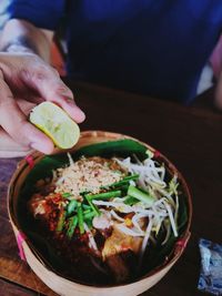 Close-up of hand holding salad in bowl on table