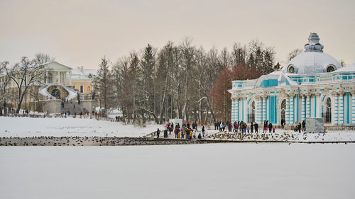 People in front of building against sky during winter