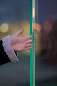 Cropped hand of woman touching glass