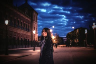 Portrait of woman against illuminated city at night