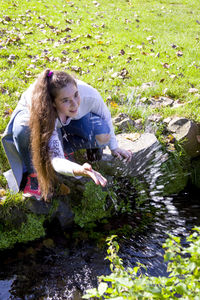 Young woman crouching by pond