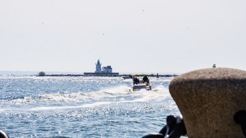 People on sea shore against clear sky
