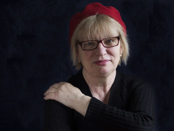 Portrait of smiling mature woman with hand on shoulder against black background