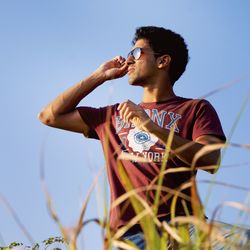 Low angle view of young man standing against clear sky