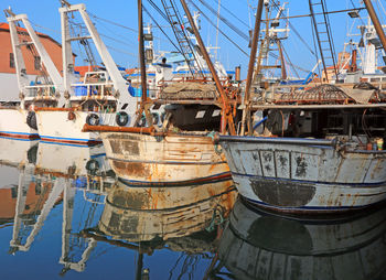 Sailboats moored at harbor against sky