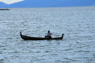 Man on boat in sea against sky