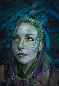 Woman with painted face against painting
