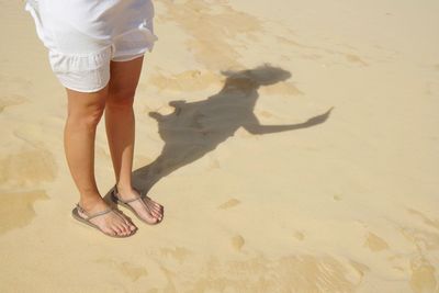 Low section of woman standing at beach