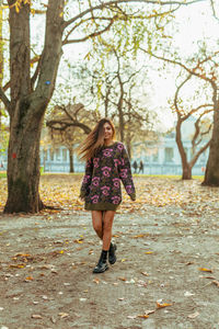 Portrait of woman tossing hair while standing at park during autumn