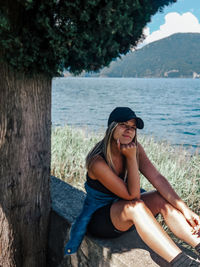 Portrait of young woman sitting on tree trunk