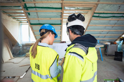 Rear view of male and female experts discussing at construction site